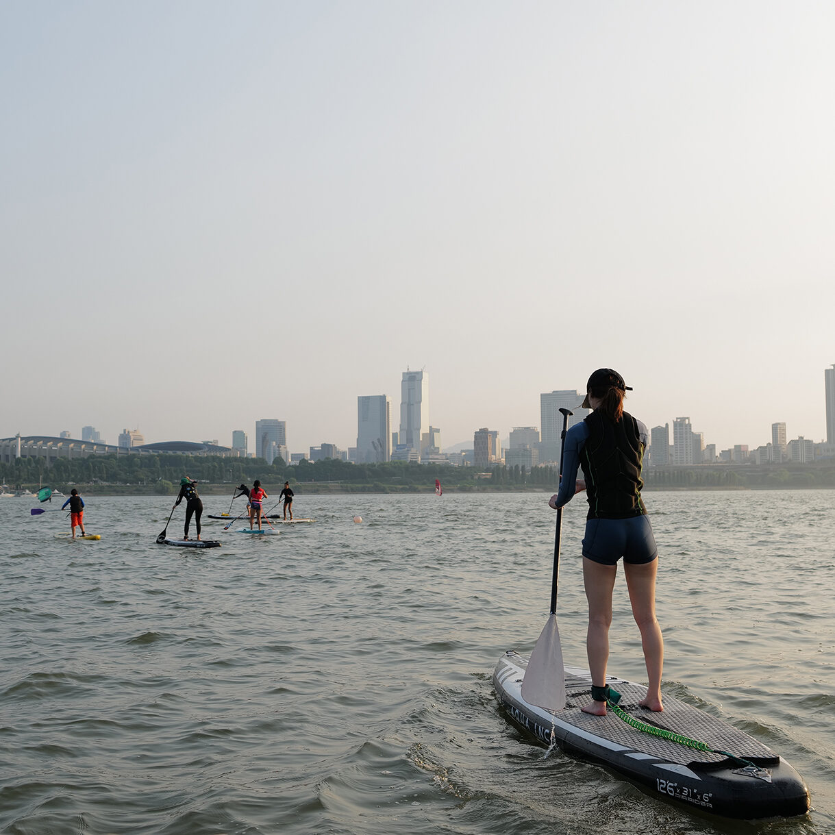 Woman practicing SUP on the Han river in Seoul South Korea. Woman joining a SUP tour right before the sun sets. Enjoying Watersport with their friends. Watersports Seoul South Korea