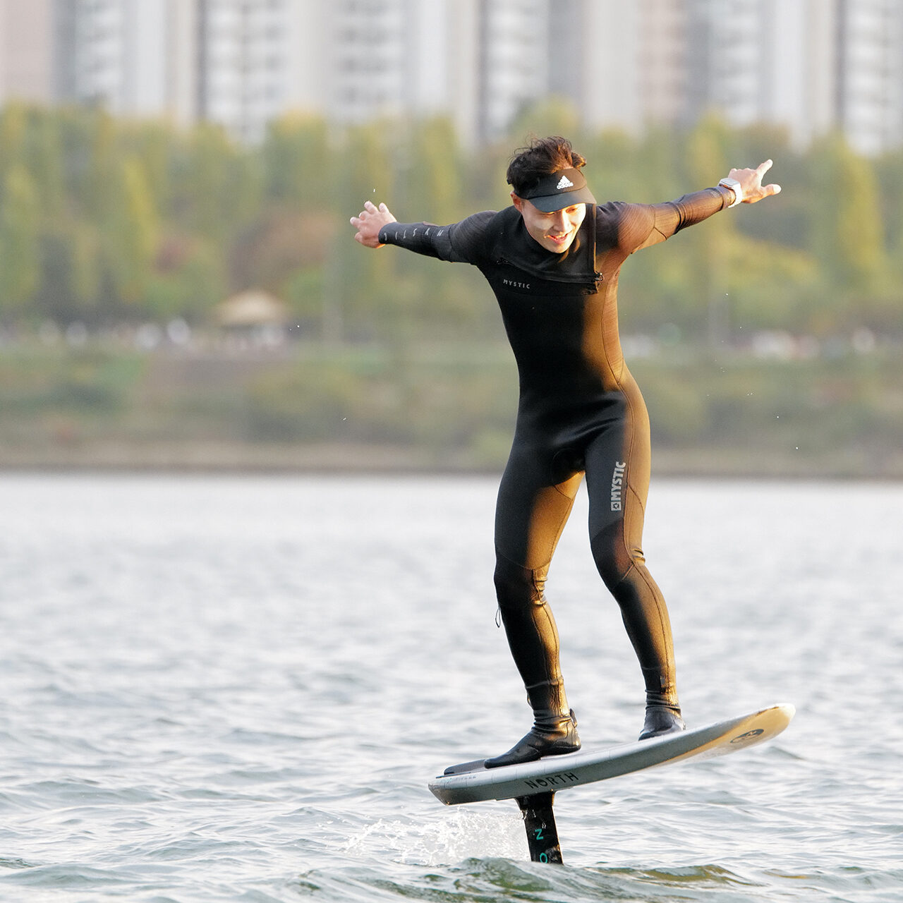 man on the Han river using foil board to do foil pumping in the middle of Seoul South Korea. Enjoying the sunset while practicing watersports on the Han river. Hi-Wind