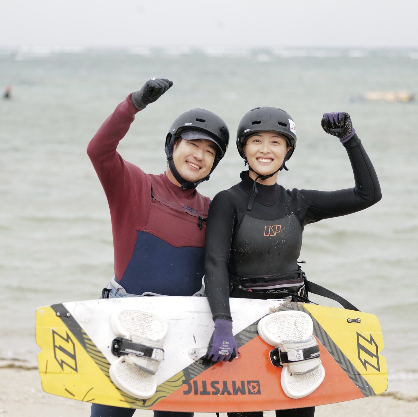 two happy students with kitesurf gear after their kiteboarding lesson, Kitesurfing