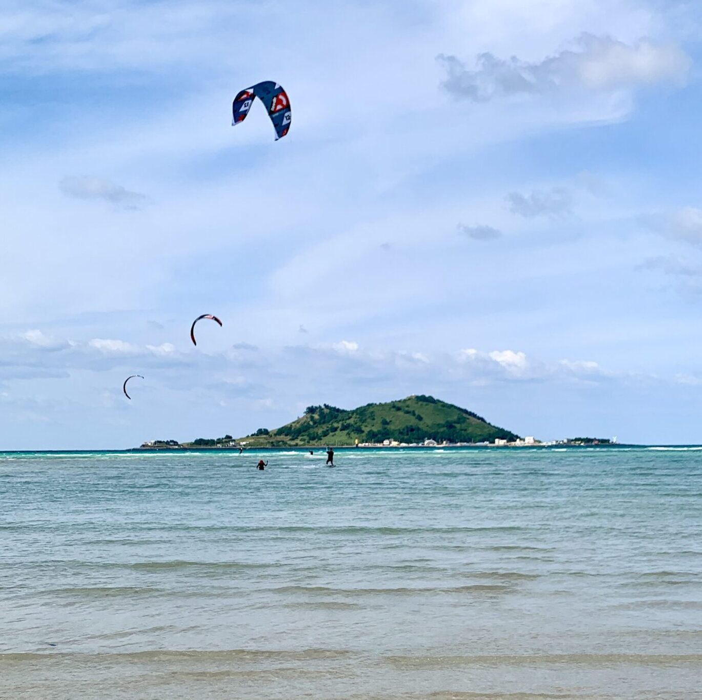 kitespot with beautiful crystal clear blue water on a beach in west Jeju Island filled with kites. Kitesurfing in Jeju Island South Korea going on a kite tour with our club