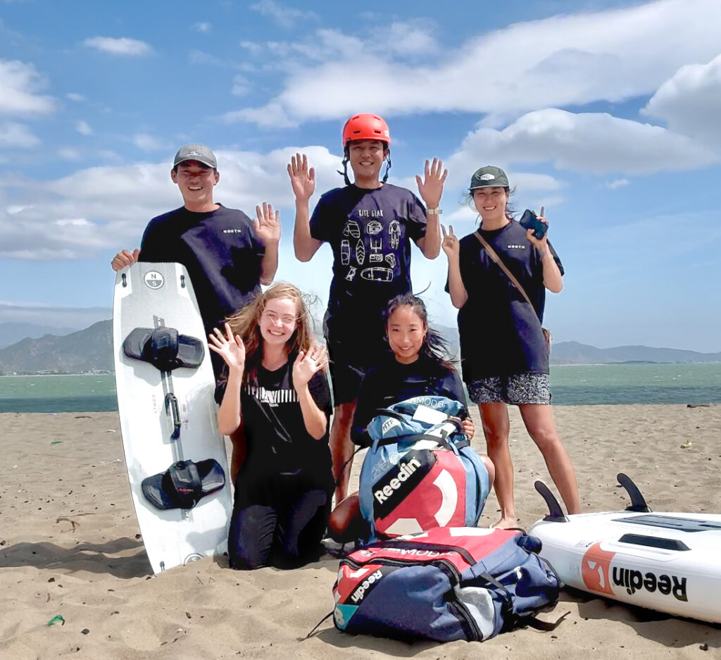 Owners, staff and instructors on the Phan Rang beach, smiling, having fun on the Vietnam winter camp. posing with kite and wing foil gear. Phan Rang Vietnam