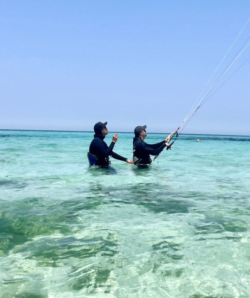 Kitesurf teacher with student in the blue water of Jeju island while teaching him Kitesurf. The crystal blue water is a perfect place to practice Watersport. Kitesurfing Jeju island South Korea