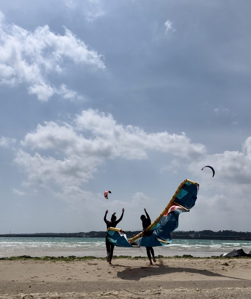 Start of the windy season in Jeju island. Start of the kitesurf season Jeju island, South Korea. Two happy people on the beach with a 7 meter reedin aluula kite.