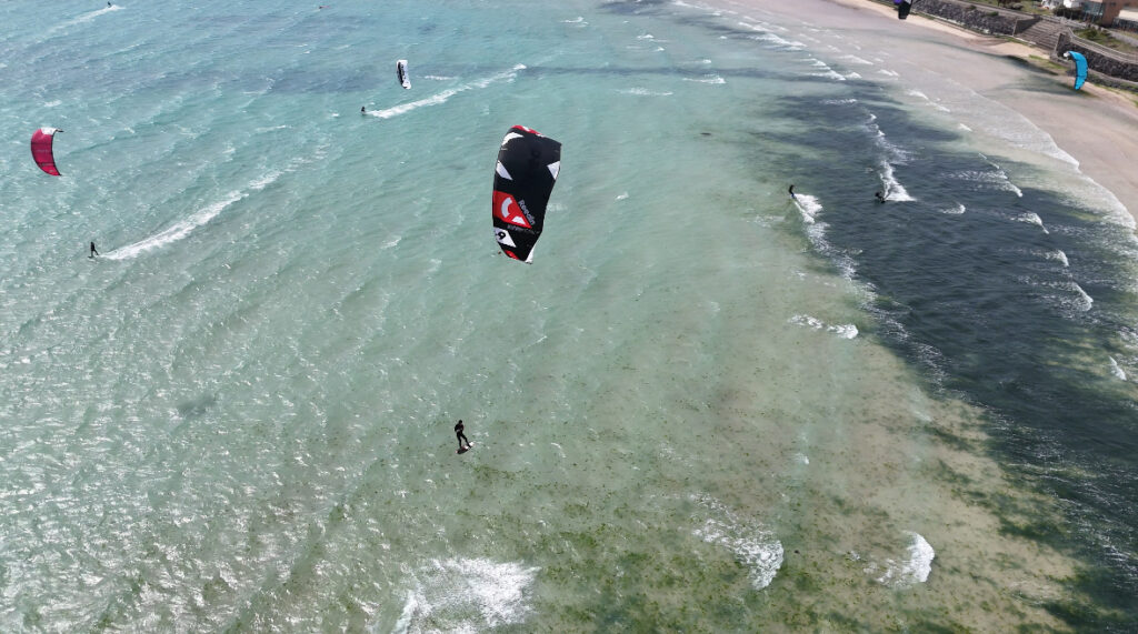 Kiters kiteboarding at Sinyang Beach Jeju Island. Start of the Kitesurf season on Jeju, South Korea, Sunny kitesurf beach. Kitesurf season